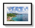 Framed photograph of a coastal scene with green hills, blue sea, and white clouds.