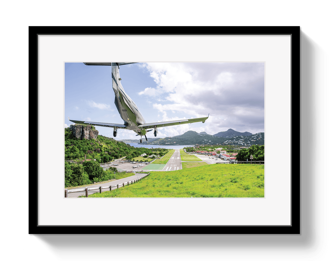 Framed photograph of a small airplane flying over a scenic landscape with mountains and roads.