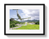 Framed photograph of a small airplane flying over a scenic landscape with mountains and roads.