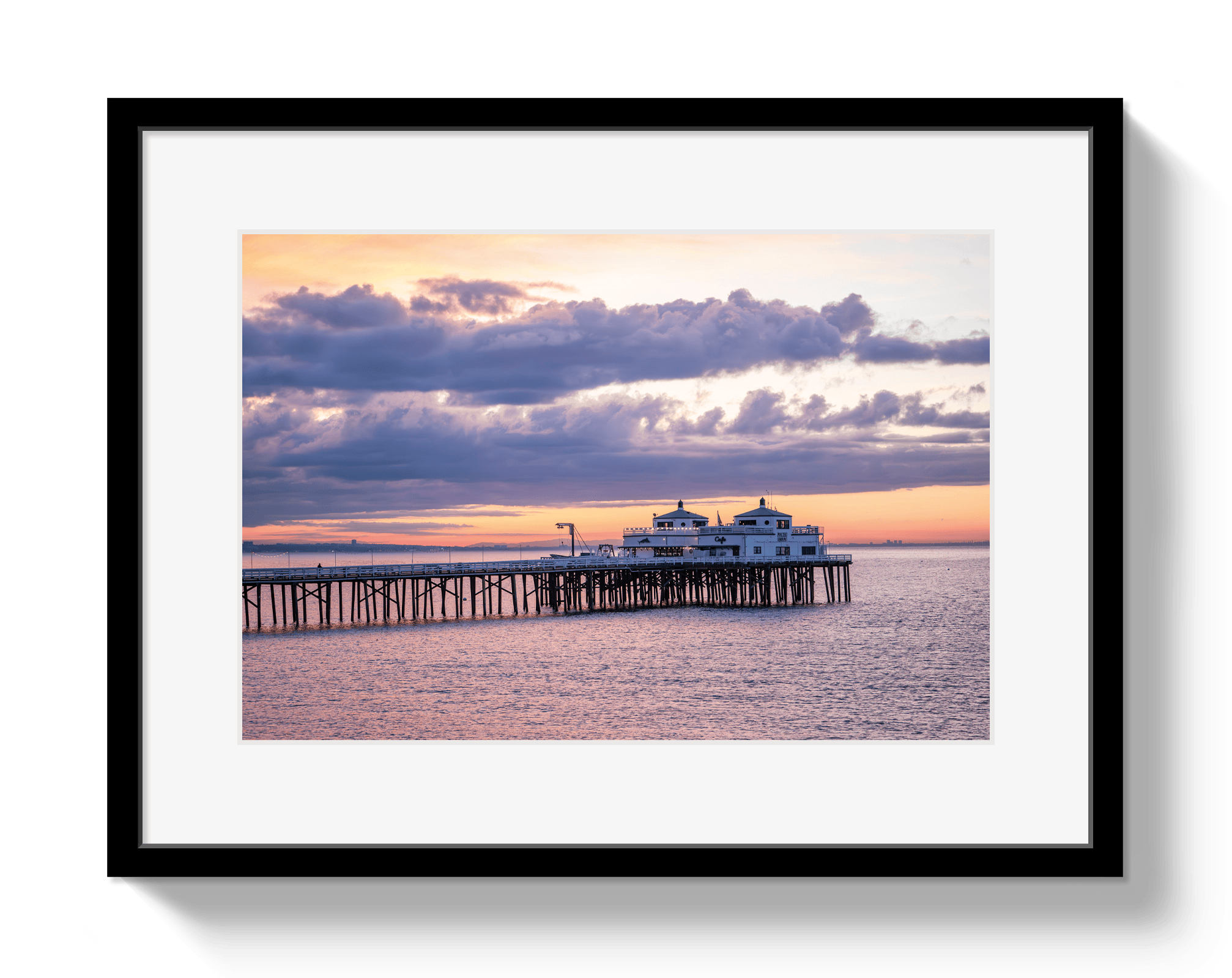 Framed photograph of a pier at sunset with a colorful sky.