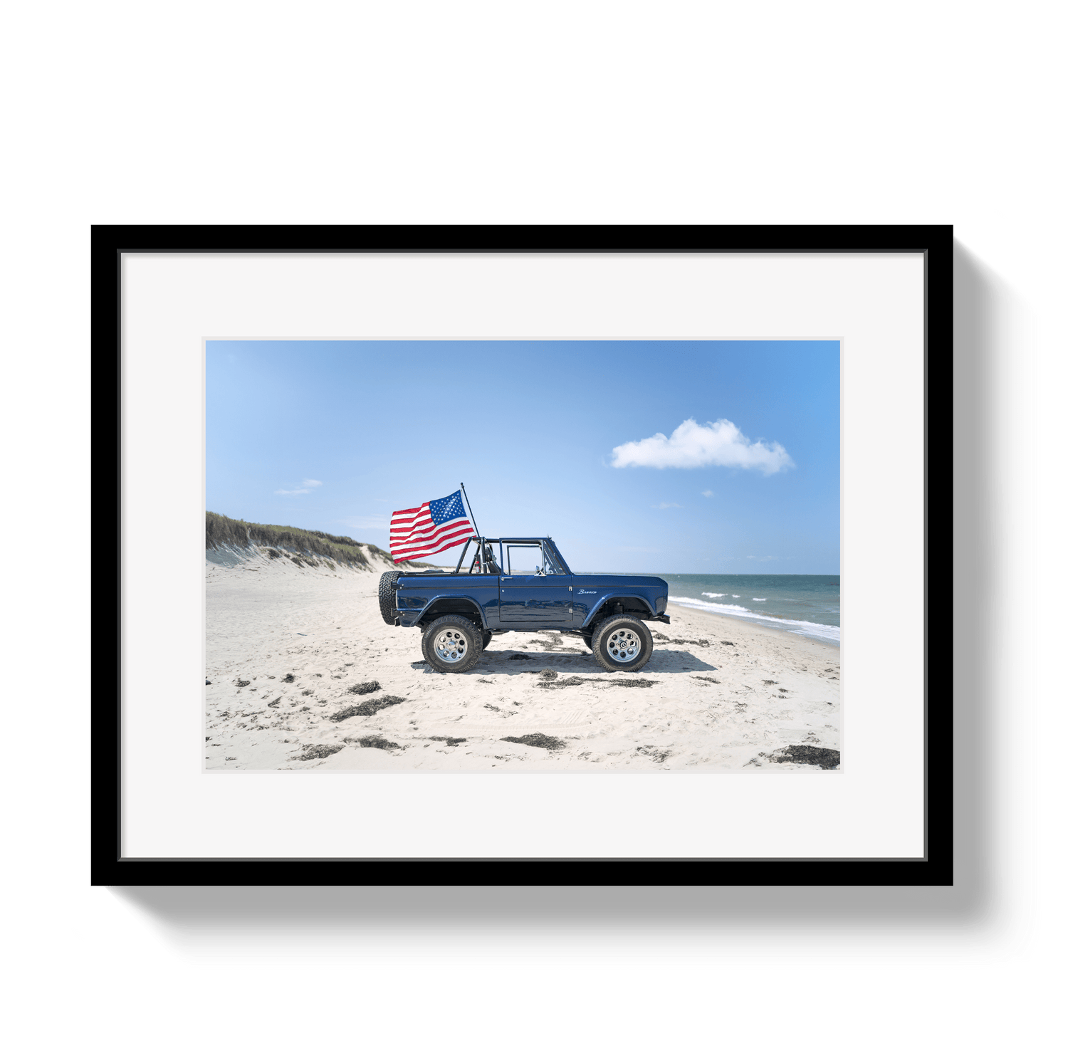 Framed photo of a blue truck with an American flag on a beach