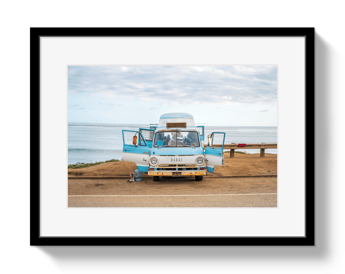 Framed photograph of a vintage camper van on a road with a scenic background.