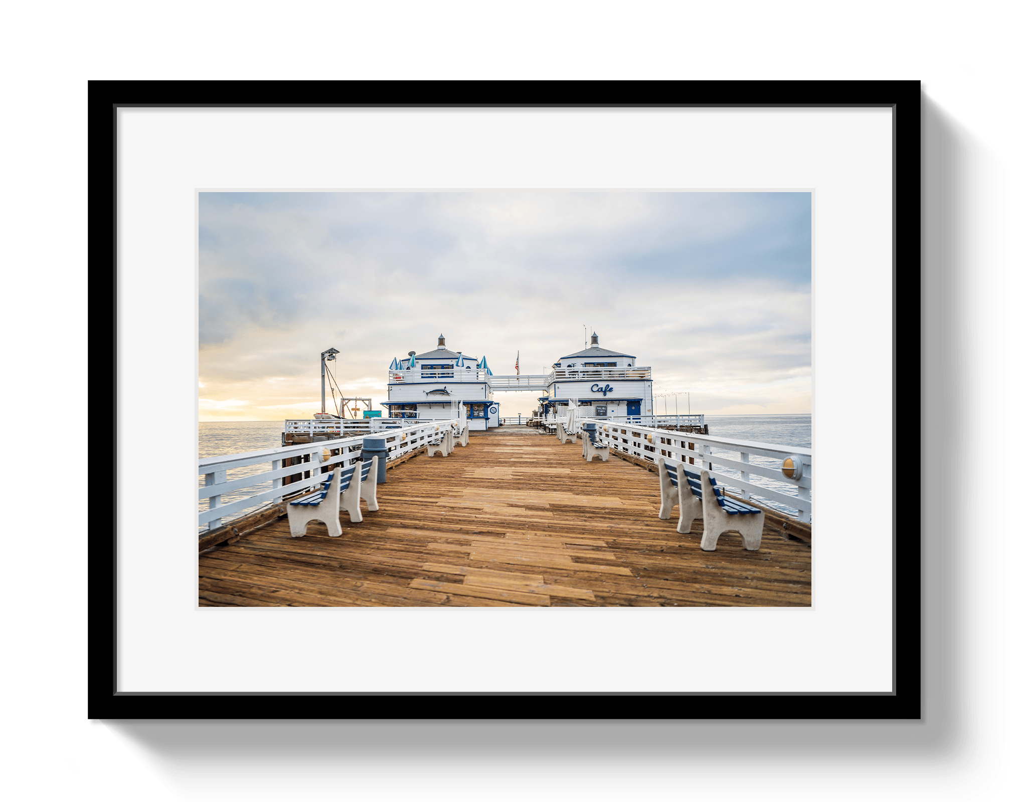 Framed photograph of a pier with boats and benches on a cloudy day.