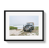 Framed photograph of a vintage Land Rover on a beach with a black frame.