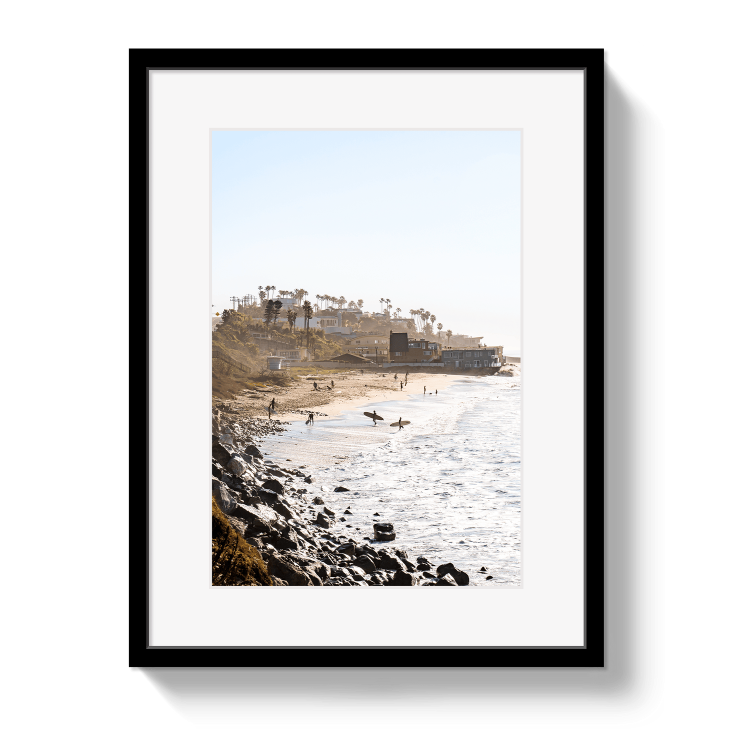 Framed photograph of a beach scene with people and a cityscape in the background.