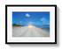 Framed photograph of a beach scene with palm trees and a clear sky.
