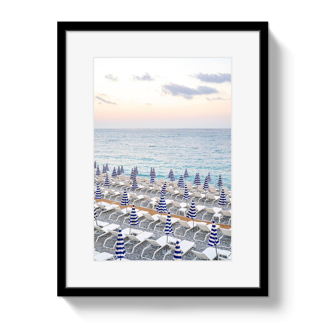 Framed artwork of a beach scene with striped umbrellas and ocean view.