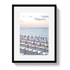 Framed artwork of a beach scene with striped umbrellas and ocean view.