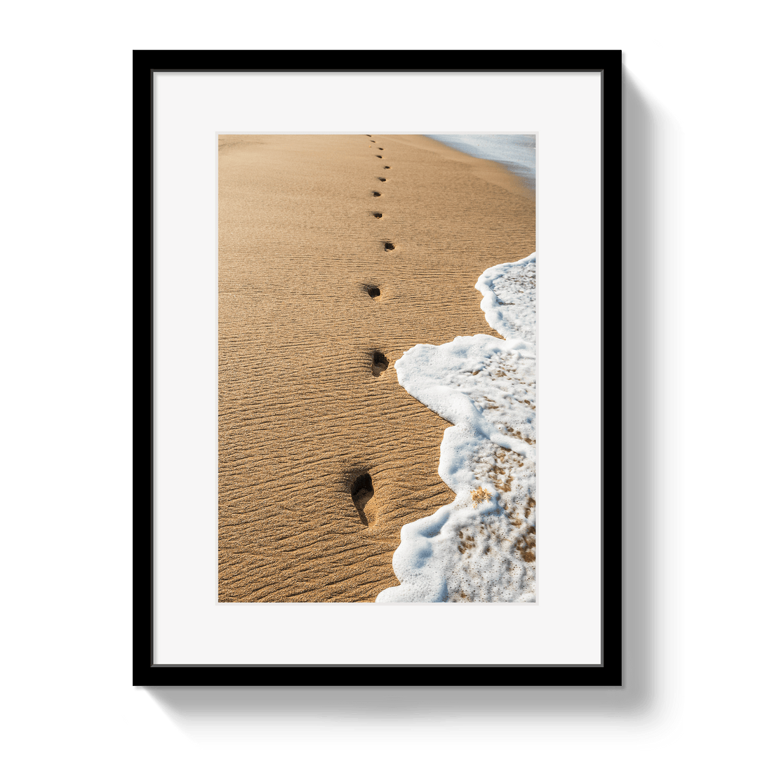 Framed artwork of footprints in sand leading to the sea