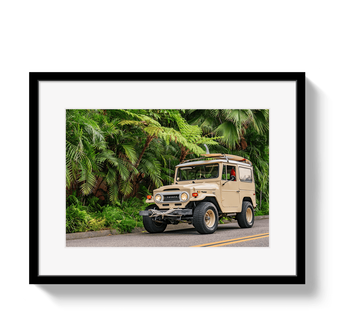 Framed photograph of a vintage SUV on a road with greenery in the background