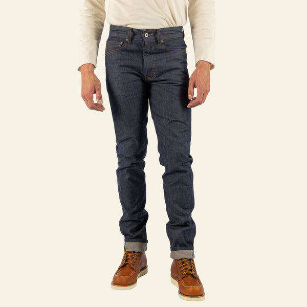 Person wearing blue jeans and brown shoes on a white background