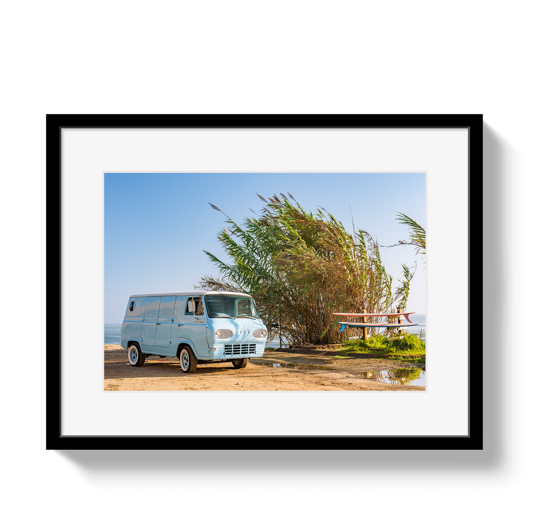 Framed photograph of a vintage van parked near tall grasses with a clear blue sky.