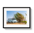 Framed photograph of a vintage van parked near tall grasses with a clear blue sky.