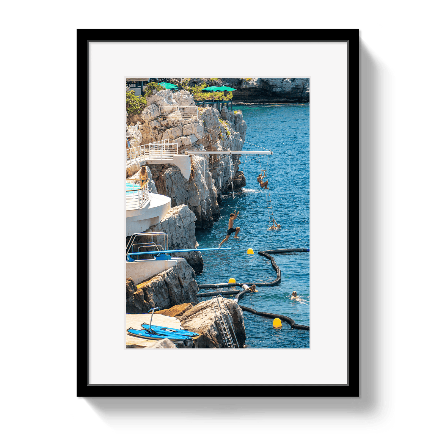 Framed photograph of people diving into a blue body of water from a rocky cliff.