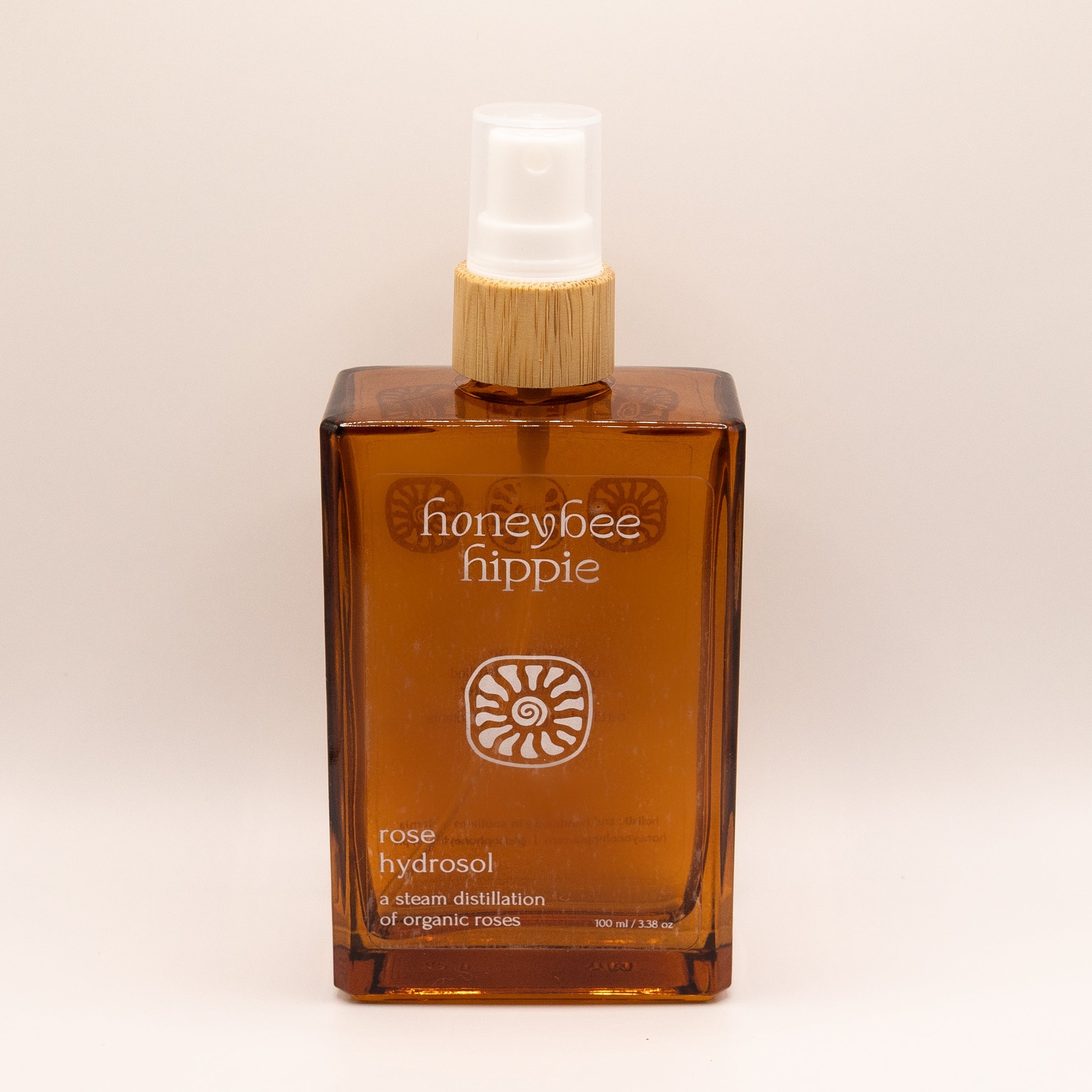 Honeybee Hippie rose hydrosol bottle on a beige background