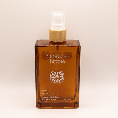 Honeybee Hippie rose hydrosol bottle on a beige background