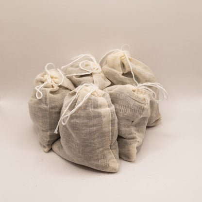 Set of five beige fabric bags with drawstrings on a light beige background