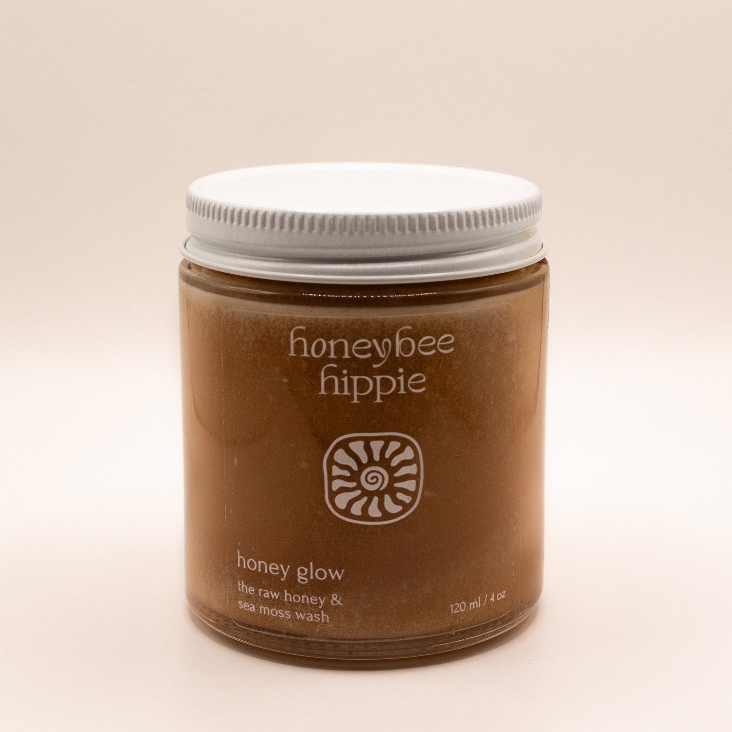 Jar of honeybee hippie honey glow product on a beige background