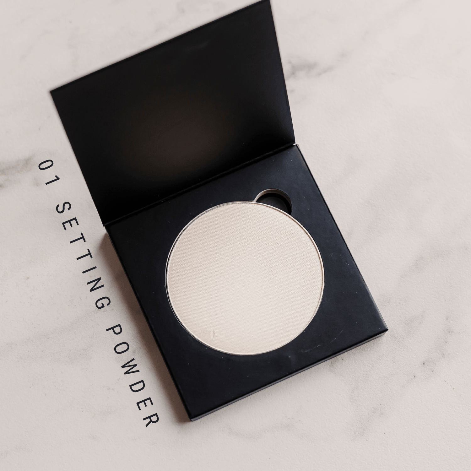 Setting powder in a black compact on a marble surface