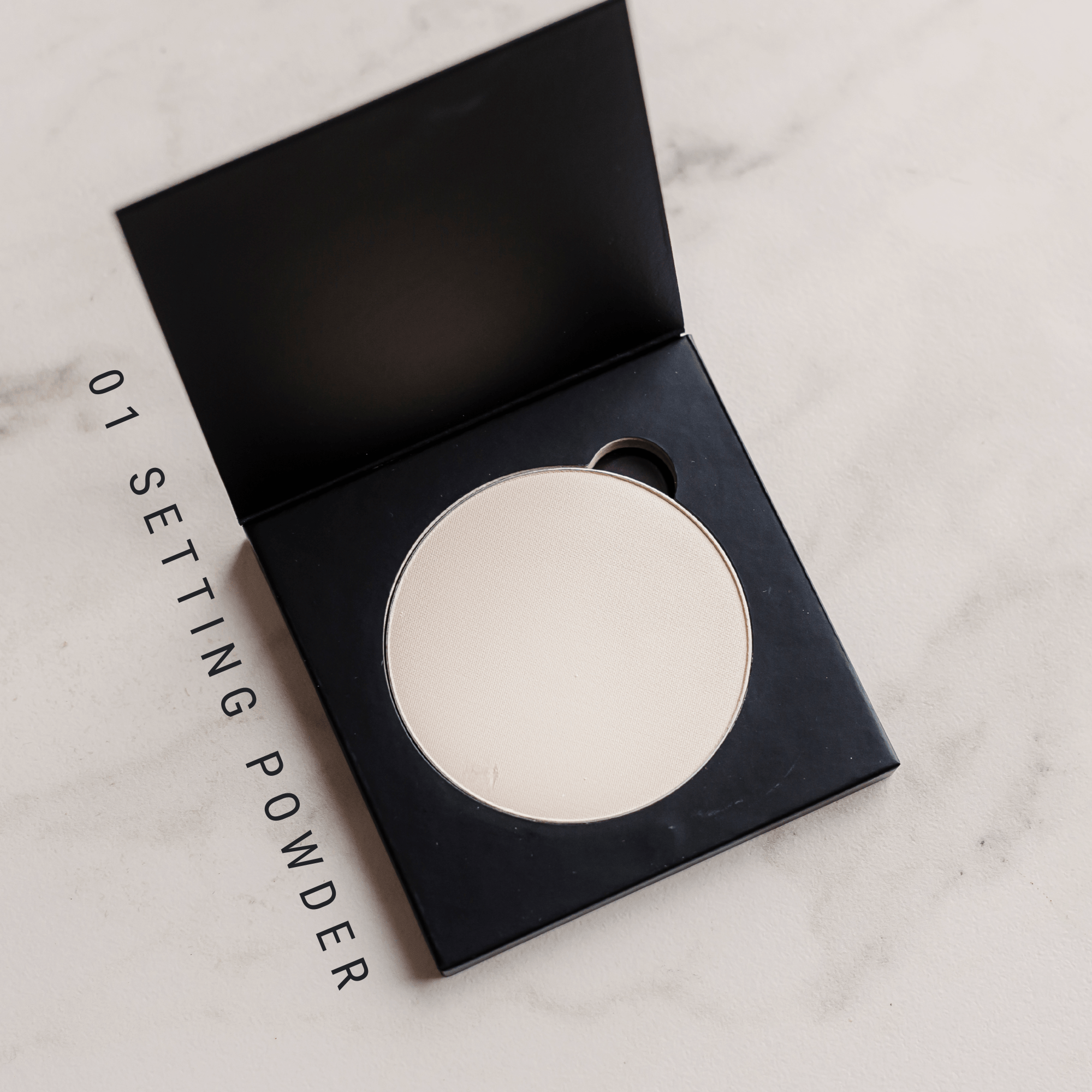 Setting powder in a black compact on a marble surface
