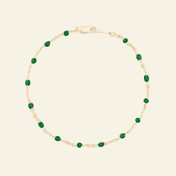 Gold bracelet with green beads on a white background