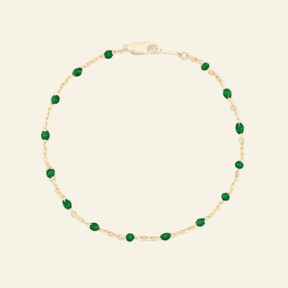 Gold bracelet with green beads on a white background