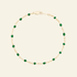 Gold bracelet with green beads on a white background