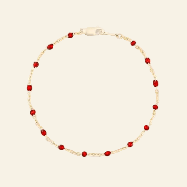 Gold bracelet with red beads on a white background