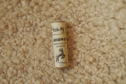 Roll of Annwn sheep tail wool lip balm on a textured beige surface