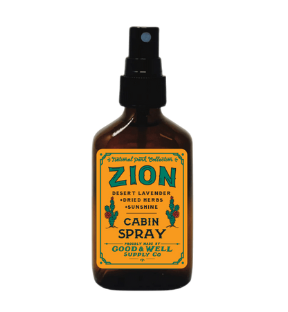 An amber glass spray bottle with a black spray top and a yellow label reading &