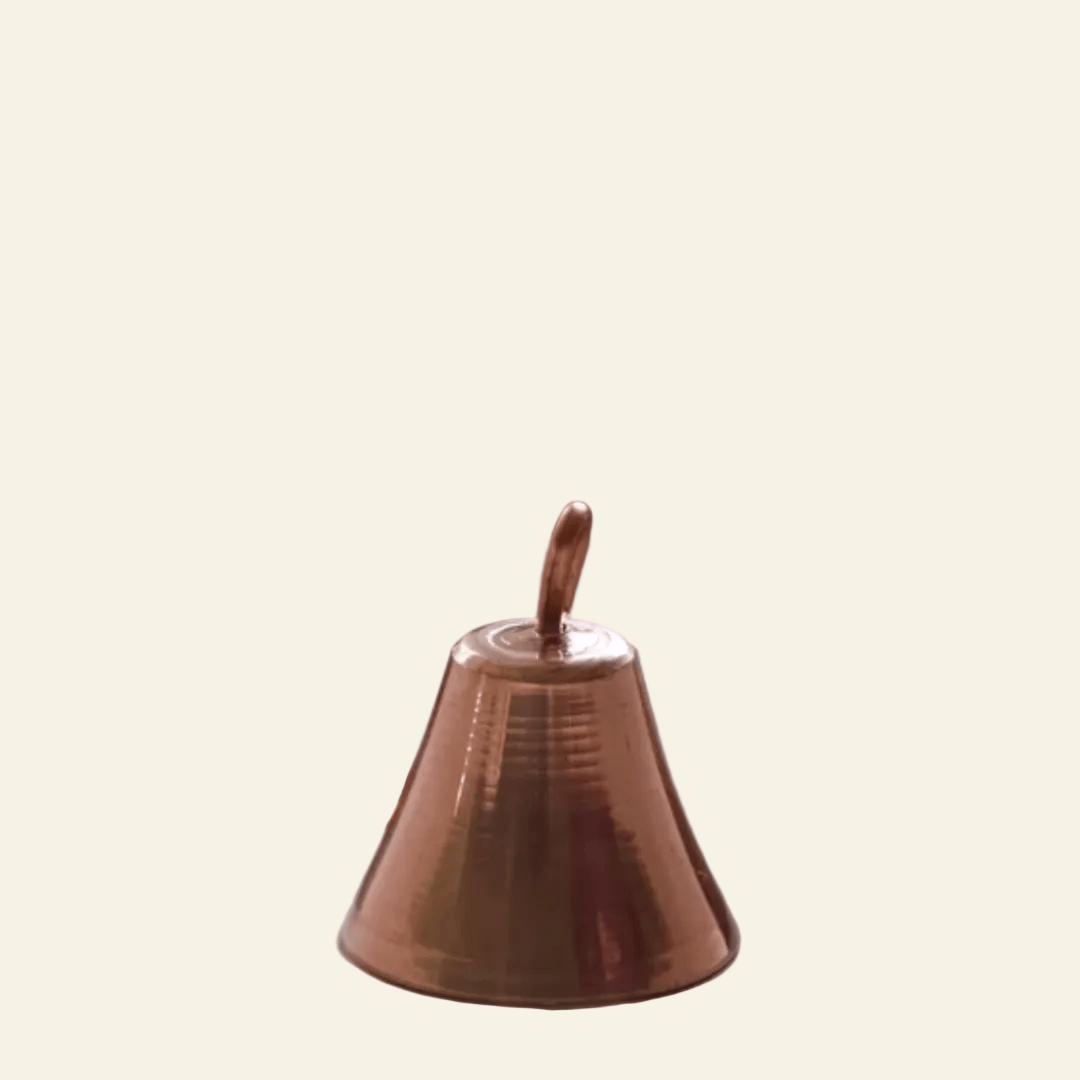 Copper bells on a textured surface with a blurred red fabric background