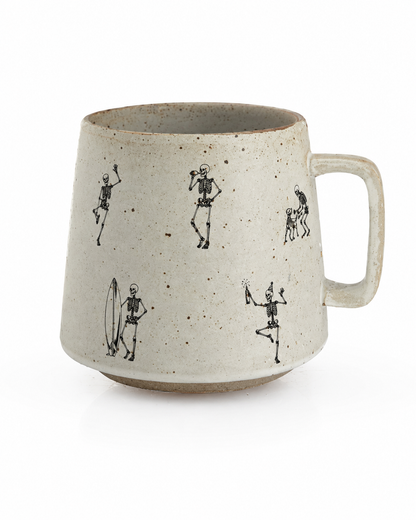 A speckled beige ceramic mug with a handle, decorated with black hand-drawn skeleton figures in various poses, shown on a white background.