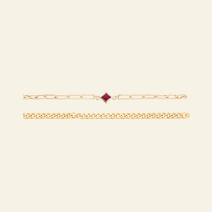 Gold bracelet with a red gemstone on a light gray background