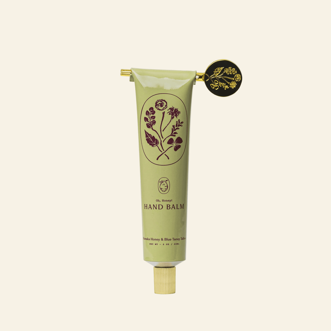 Green hand balm tube with floral design on a light gray background