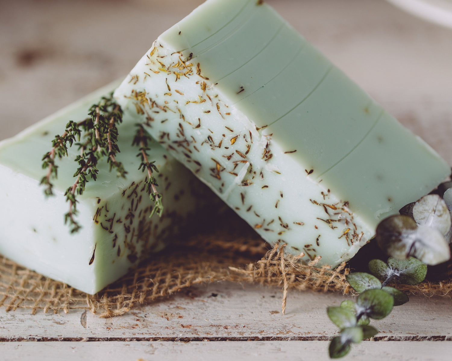 Green soap with herbs on a rustic wooden surface