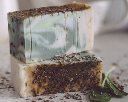 Two bars of soap with a natural, earthy texture on a light surface.
