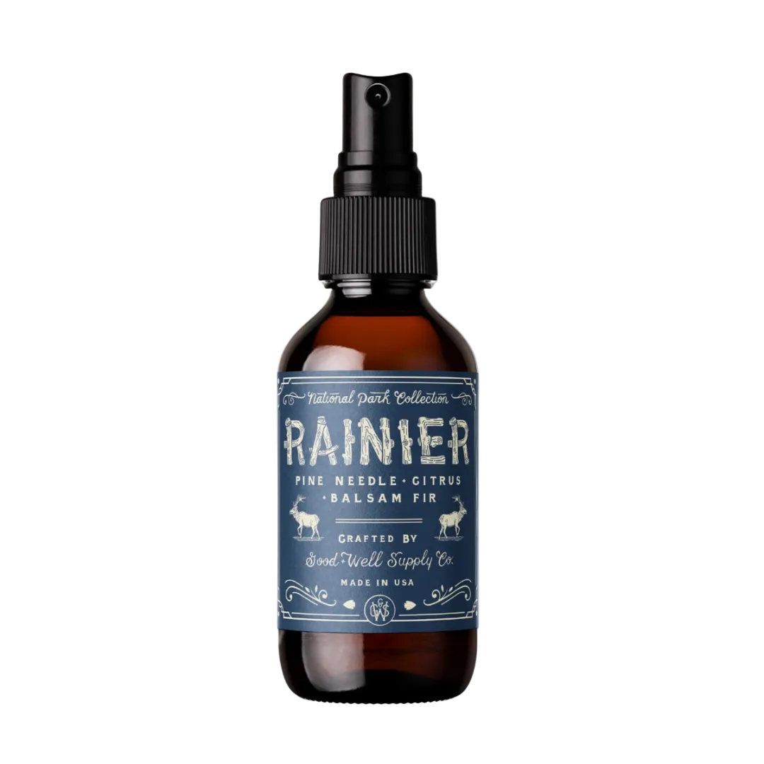 An amber glass spray bottle with a black pump dispenser and a dark blue label reading &