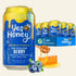A 11 fl oz can of Yes Honey Berry beverage in the foreground with a 12-pack display box and several cans behind it on a white studio background. Blueberries, honeycomb, and honey are shown as flavor/ingredient props.
