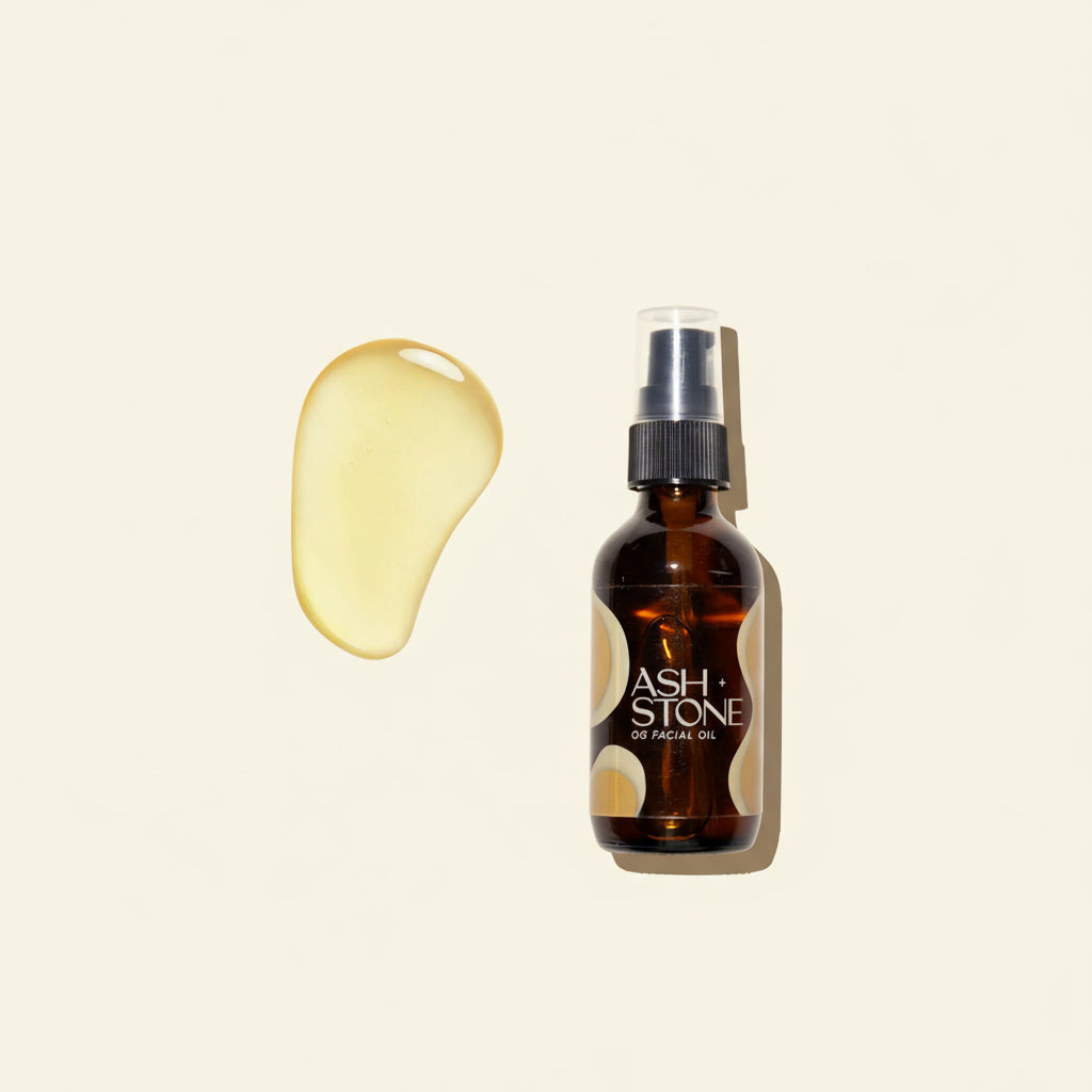 Brown glass bottle of Ash + Stone facial oil with a droplet of oil on a white background