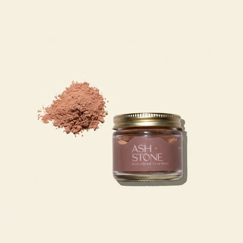 Jar of Ash + Stone clay mask with a heaped amount of pink clay on a white background