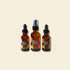 Three amber glass bottles with black lids on a white background, featuring the brand &
