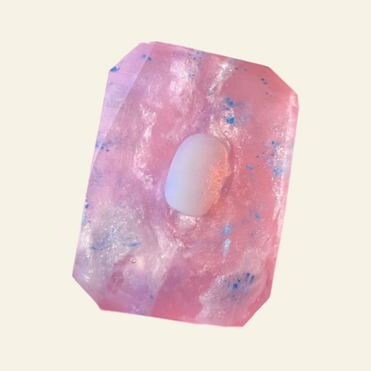Pink crystal with a white sphere inside, held in a hand with a natural background