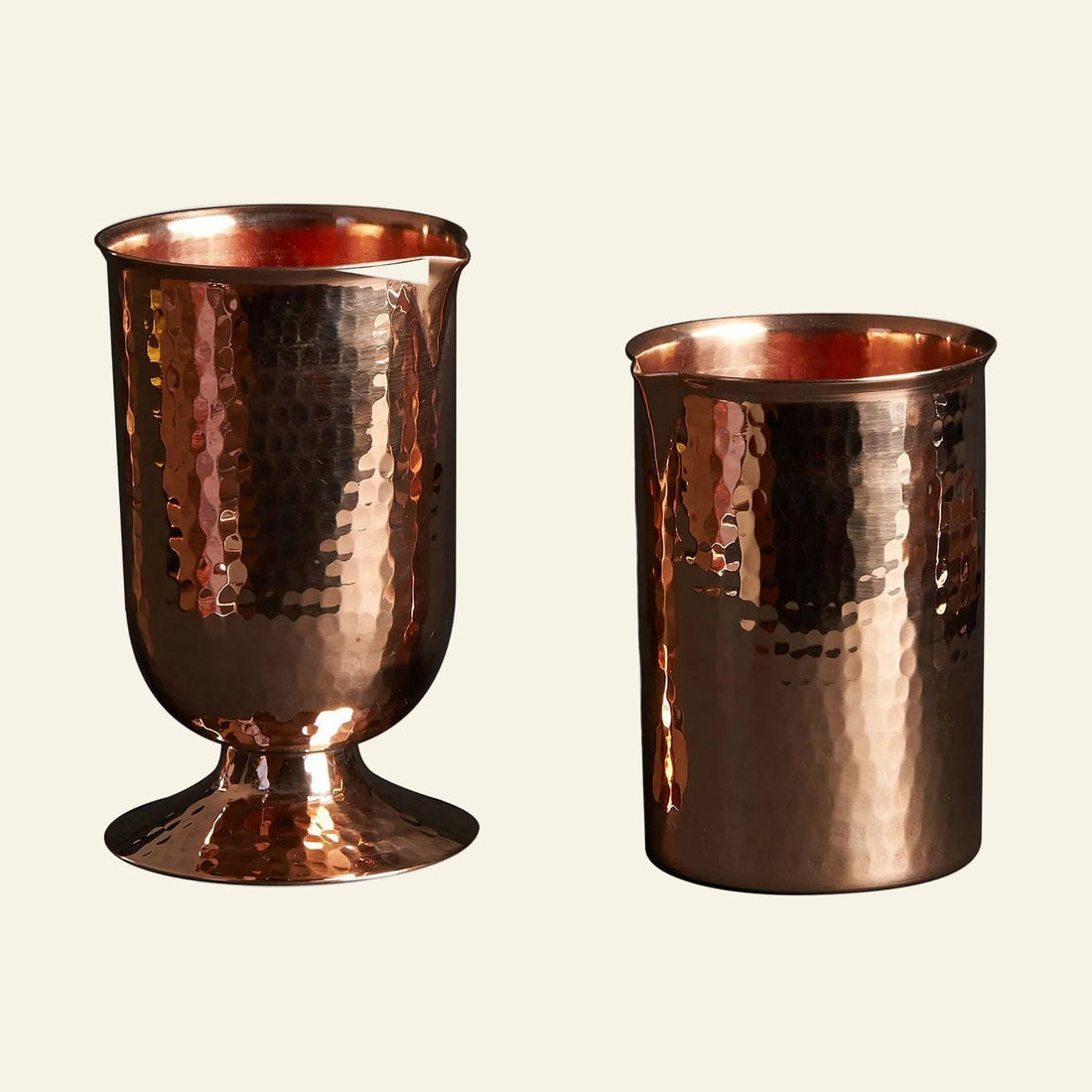 Two copper tumblers with a textured surface on a white background