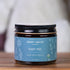 Jar of Chagrin Valley Soap & Salve Company Baby Me! Baby Body Balm on a wooden surface with a blurred background.