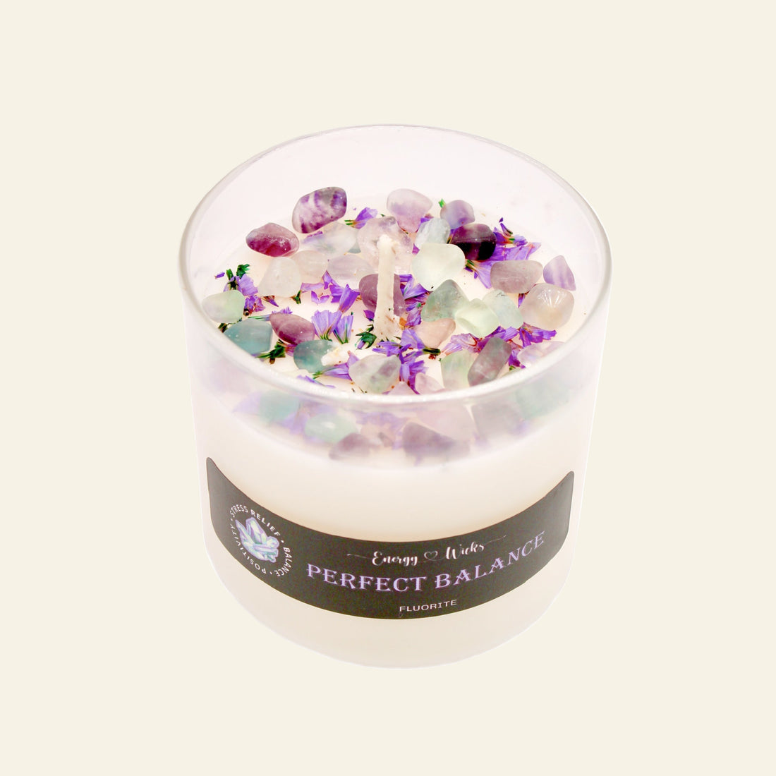 Candle with colorful crystals and a label on a white background
