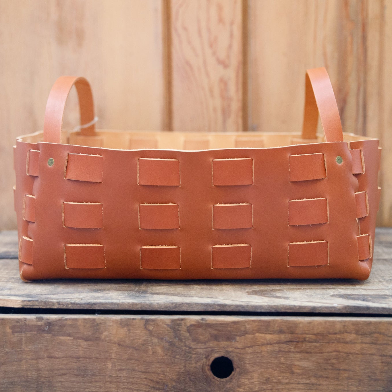 Brown woven basket with handles on a wooden surface