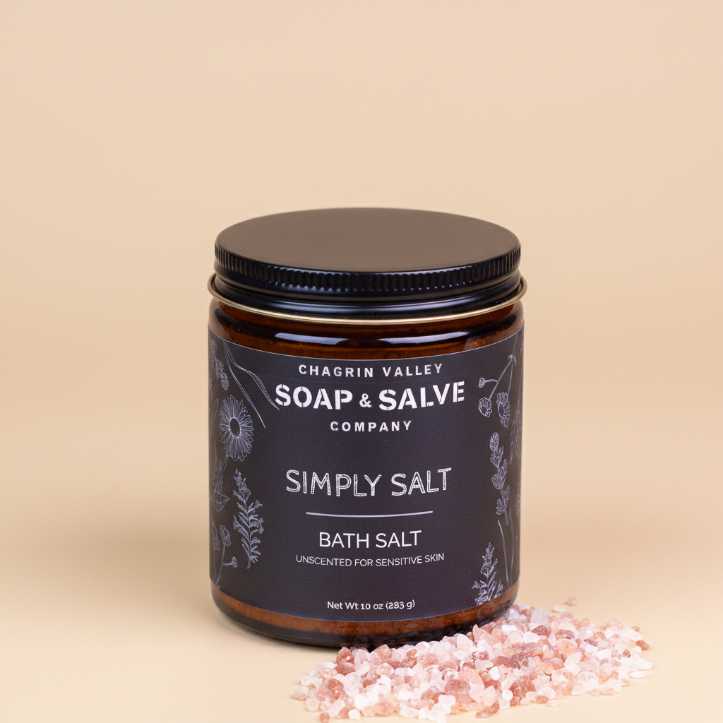 Chagrin Valley Soap &amp; Salve Company Simply Salt Bath Salt in an amber glass jar with a black lid and black label, shown on a dark reflective surface with pink salt crystals in front.