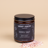 Chagrin Valley Soap & Salve Company Simply Salt Bath Salt in an amber glass jar with a black lid and black label, shown on a dark reflective surface with pink salt crystals in front.