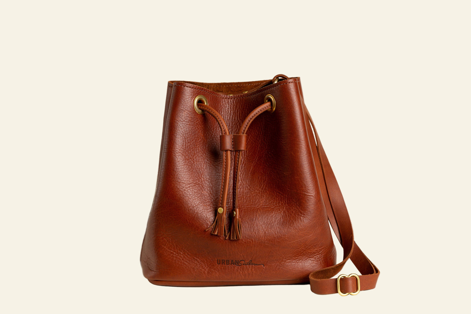 Brown leather bucket bag with a strap on a white background