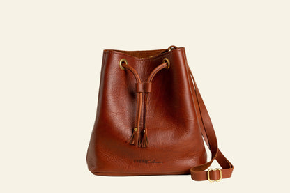 Brown leather bucket bag with a strap on a white background